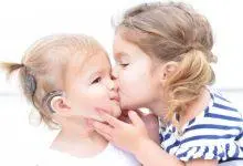 طفل يستخدم سماعة، يقبله طفل آخر.