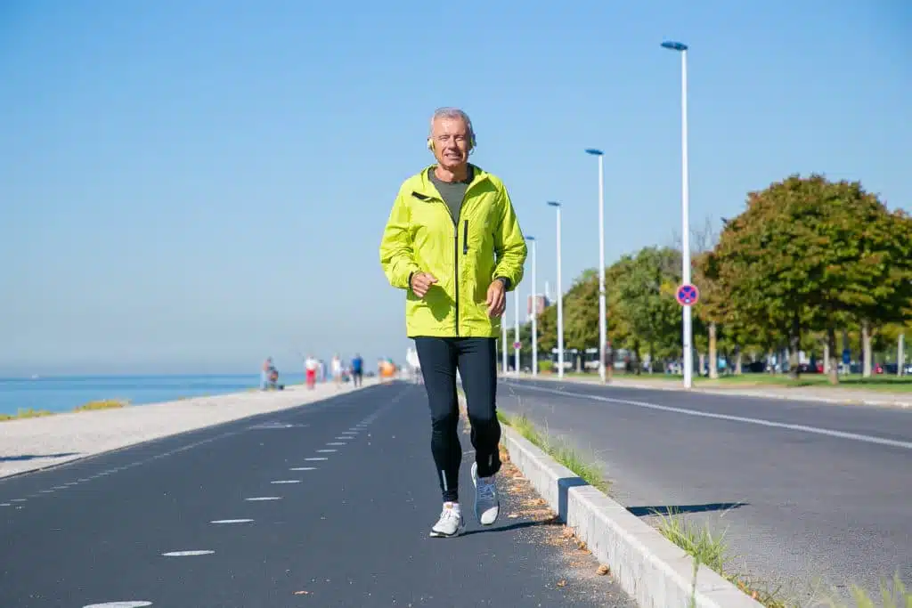 happy excited mature man in wireless headphones jogging