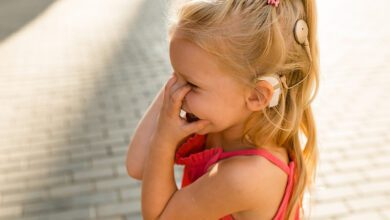 Enfant souriant portant un appareil auditif.