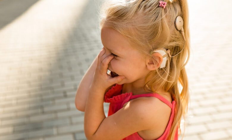 Enfant souriant portant un appareil auditif.