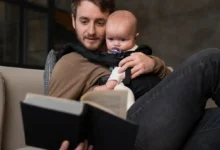 Homme lisant un livre à un bébé.