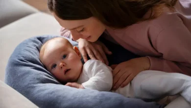 Mère souriante regardant bébé sur oreiller bleu.