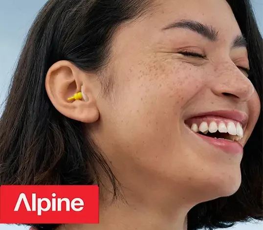 Femme souriante portant des bouchons d'oreilles Alpine.